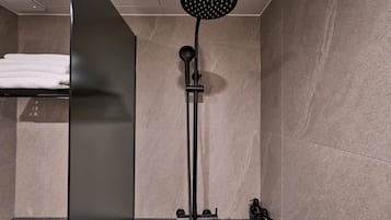 A modern bathroom with a shower, a towel rack, and a wall-mounted control panel.