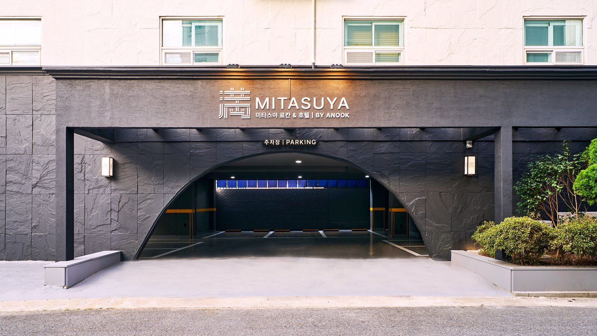 A building entrance with a sign for 'MITSASUYA' and a 'PARKING' sign.