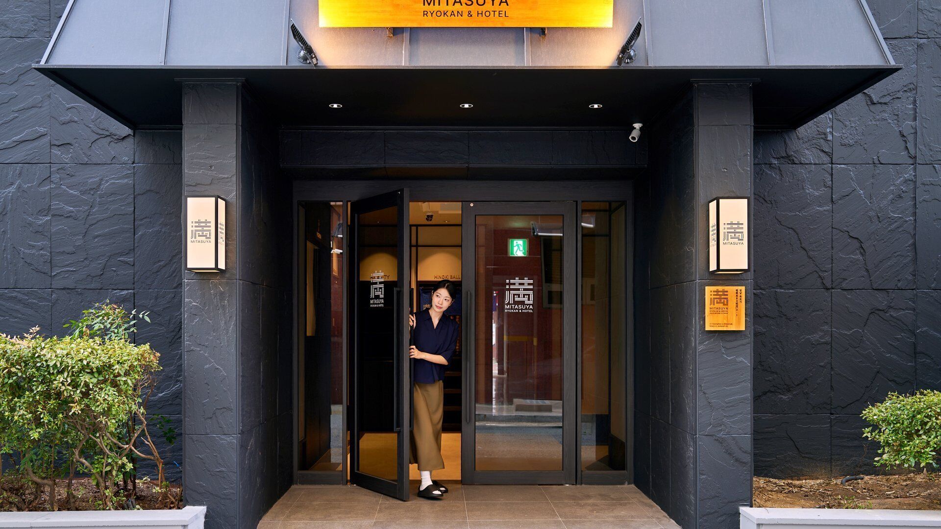 A hotel entrance with a modern design, featuring a glass door and a signboard above.