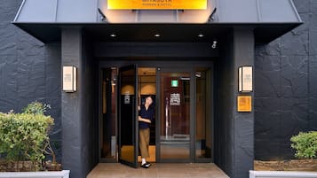 A hotel entrance with a modern design, featuring a glass door and a signboard above.