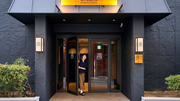 A hotel entrance with a modern design, featuring a glass door and a signboard above.