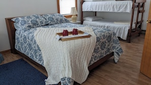 Ein Bett mit einem gemusterten Überwurf, einer gestrickten Decke und einem Tablett mit zwei roten Tassen.
