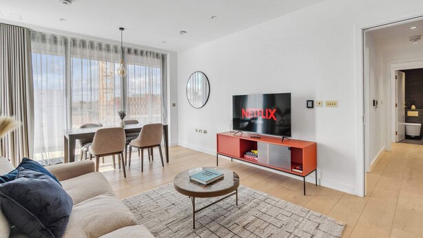 Ein modernes Wohnzimmer mit Flachbildfernseher, Essbereich und Blick auf die Stadt.