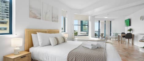A modern hotel room with a large bed, bedside tables, a desk, and a view of the city.