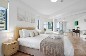 Een moderne hotelkamer met een groot bed, nachtkastjes, een bureau en uitzicht op de stad.