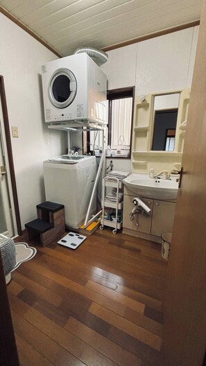 A compact bathroom with a washing machine, a sink, and a small step stool. - niconicoHOUSE. One group per day on an exclusive-use basis. A detached house with a spacious garden and a starry sky. Sand Bath Hot Spring · Near Japan's Southernmost Station (指宿市)