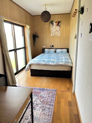 A room with a bed, a desk, a chair, a window with curtains, and a hanging light fixture. - niconicoHOUSE. One group per day on an exclusive-use basis. A detached house with a spacious garden and a starry sky. Sand Bath Hot Spring · Near Japan's Southernmost Station (指宿市)