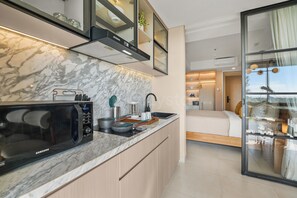 A modern kitchen with a built-in microwave, a sink, and a countertop with various kitchen items. - Jasmine by Kozystay - Nusa Dua (Badung)