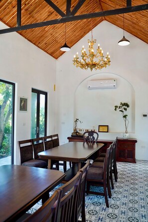 A dining area with a long wooden table, multiple chairs, a chandelier, and an arched ceiling. - Laman Riverside (Hoa Lu)