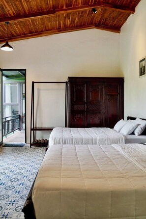 A bedroom with a wooden ceiling, two beds with white bedding, a dark wooden wardrobe, and a patterned floor. - Laman Riverside (Hoa Lu)
