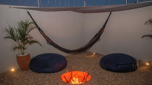 A hammock, two bean bags, a fire pit, and a potted plant in a patio area. - Paracuru Stay beach house with pool for families and groups of friends. (Paracuru)