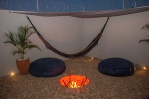 A hammock, two bean bags, a fire pit, and a potted plant in a patio area. - Paracuru Stay beach house with pool for families and groups of friends. (Paracuru)