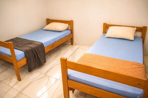 Two wooden single beds with blue mattresses and pillows, a brown blanket on one, and a tiled floor. - Paracuru Stay beach house with pool for families and groups of friends. (Paracuru)