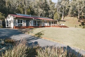 Eingeschossiges Haus mit rotem Dach, einer überdachten Veranda und einer Anlage von Solarmodulen.