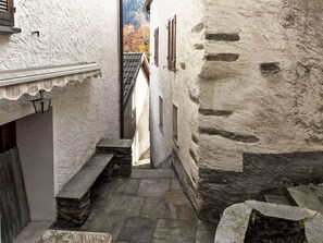 A narrow stone pathway leading to a building with a steeply pitched roof and wooden shutters. - Casa Onsernone by Interhome (Onsernone)