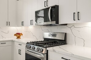 A kitchen with white cabinets, a black microwave, and a stainless steel stove. - Clean, new built spacious house, downtown, close to everything (Houston)