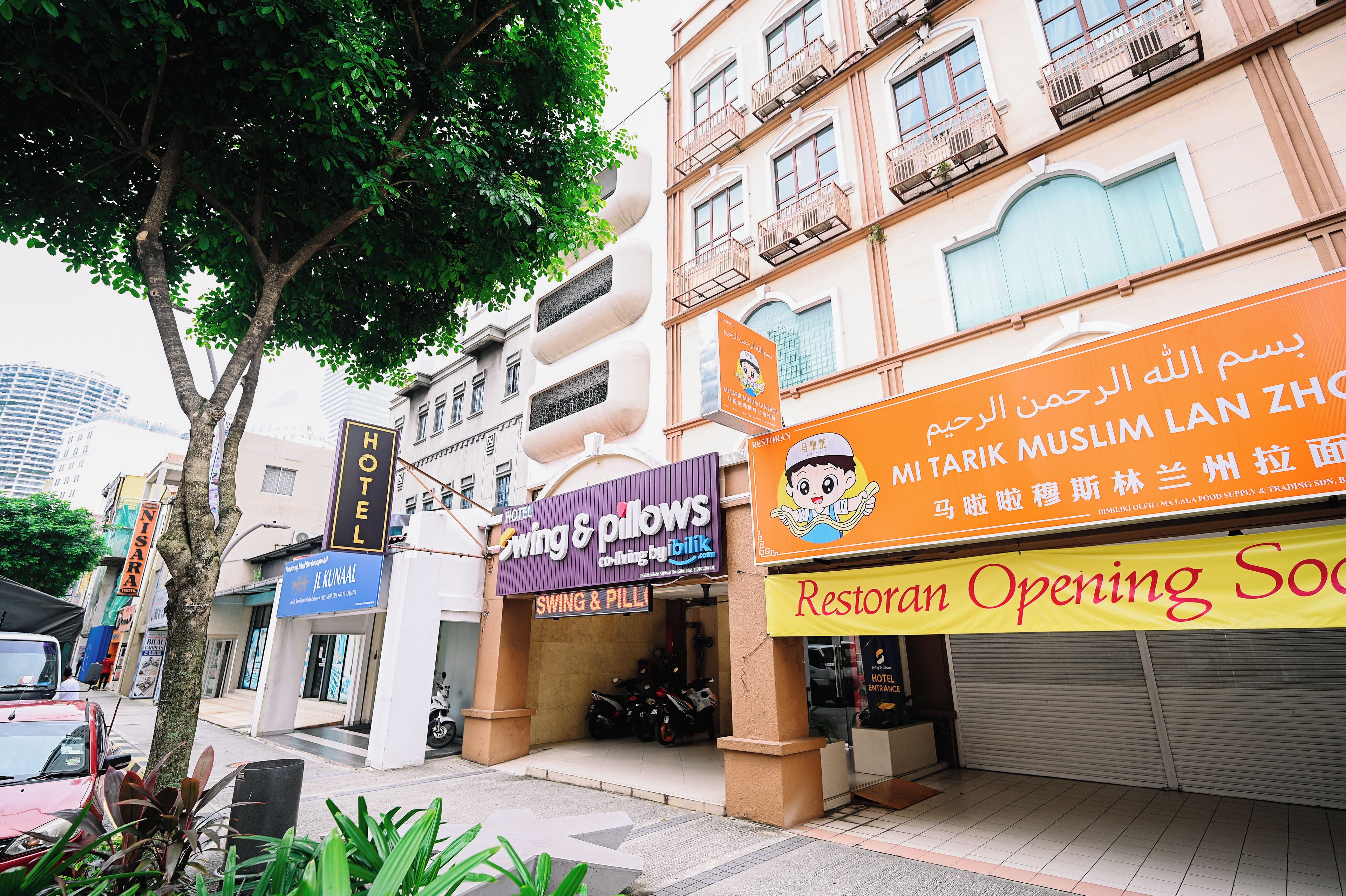 A hotel entrance with a sign for 'Hotel Swing & Pillow' and 'Restoran Opening Soon'.