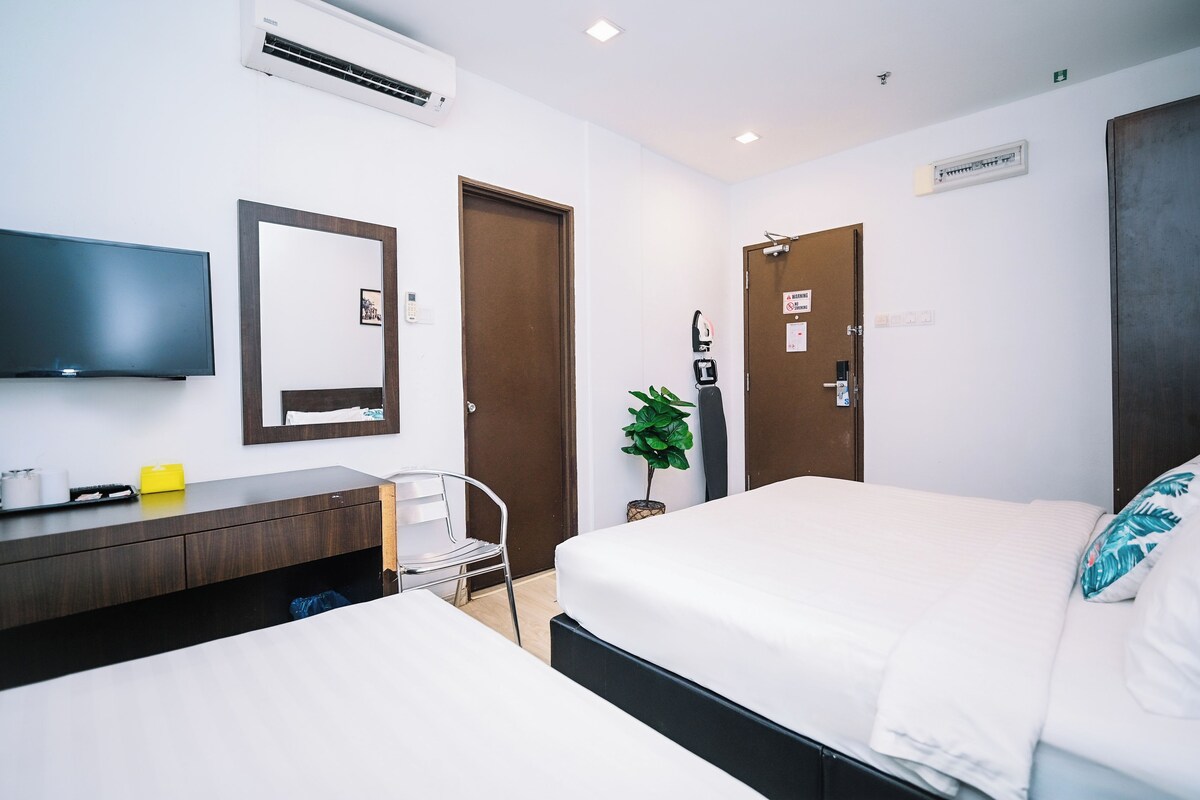 Una habitación de hotel con cama, escritorio, silla, televisor y aire acondicionado.