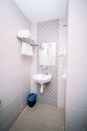 Un baño con un lavabo blanco, toallero, espejo y ducha.