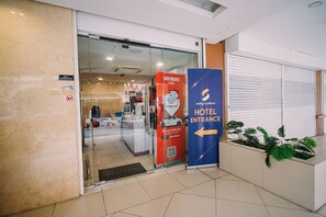 A hotel entrance with a glass door, a red promotional sign for airasia ride, and a blue directional sign for the hotel entrance. - Swing & Pillows - Dataran Merdeka KL (Kuala Lumpur)