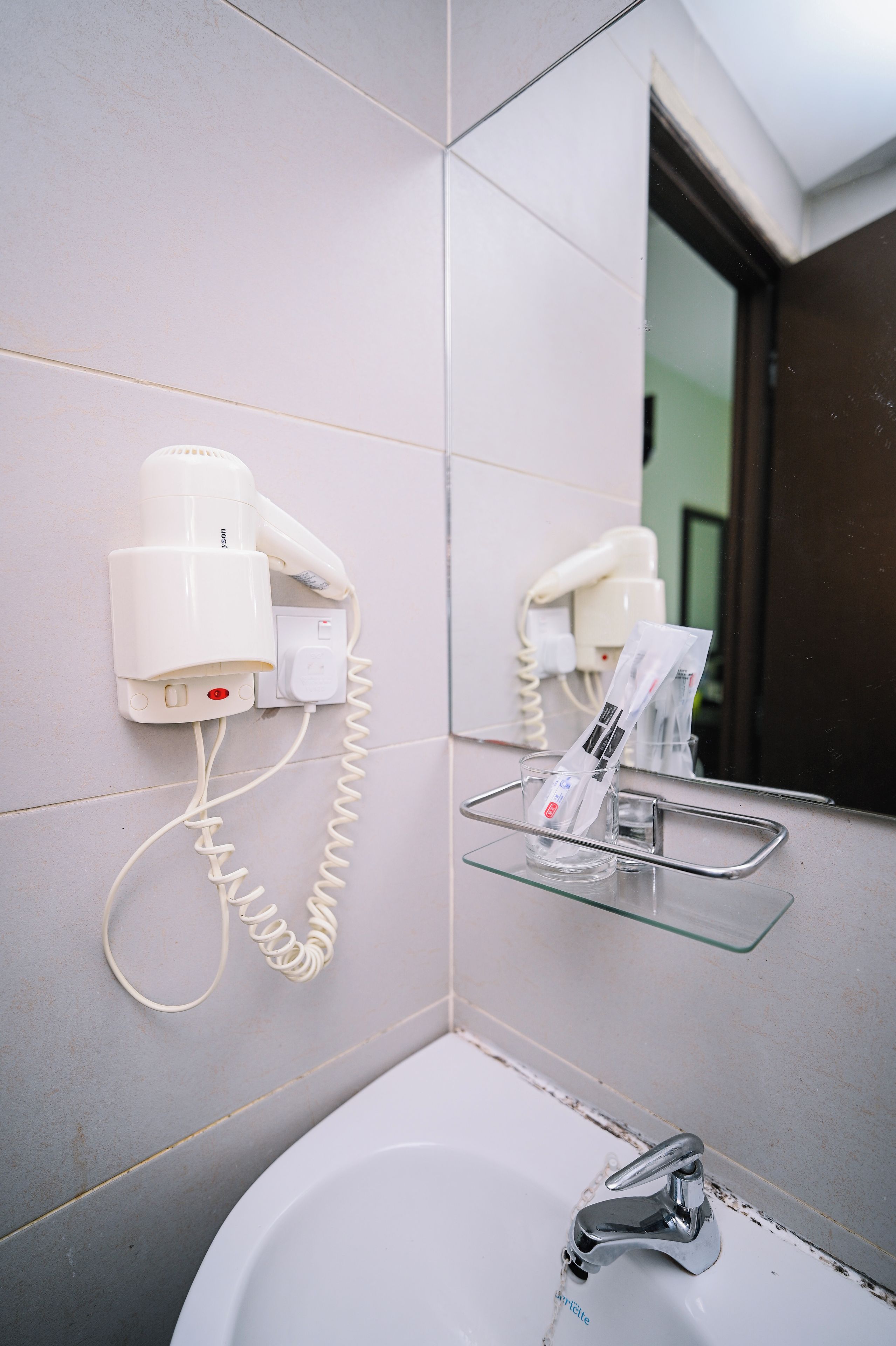 A bathroom with a white sink, a hairdryer, and a telephone mounted on the wall.