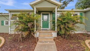 Uma casa com porta verde e varanda com degraus.