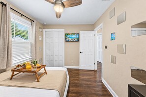 A hotel room with a bed, a breakfast tray, a ceiling fan, and a view of the outdoors through the window. - Spacious 5BR Retreat w/ Game Room + Patio (Tampa)