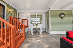 A covered patio with a wooden staircase, a dining table with chairs, and a clock on the wall. - Spacious 5BR Retreat w/ Game Room + Patio (Tampa)