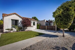 A residential property with a well-maintained lawn, a driveway leading to a gated entrance, and a clear sky. - Serene LA 2BR Retreat with BBQ & Outdoor Lounge (Los Angeles)