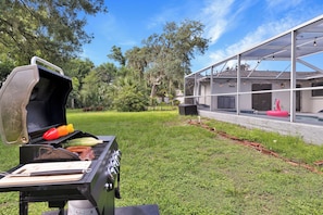 Ein Garten mit Grill, Schwimmbecken und überdachter Terrasse.