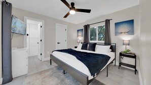 A bedroom with a bed, a ceiling fan, a window with curtains, and artwork on the walls. - Pool Days, Sunshine & Memories for Everyone (Temple Terrace)