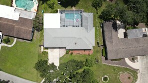 Eine Vogelperspektive eines Wohnhauses mit Schwimmbad, Tennisplatz und gepflegtem Rasen.