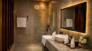 A modern bathroom with a glass-enclosed shower, a large mirror, and a vanity with a sink and towel. - Krisna Osea Villas  (Buleleng)