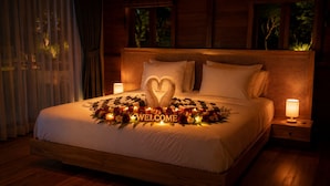 A neatly made bed with a welcome mat, floral arrangement, and a heart-shaped centerpiece. - Krisna Osea Villas  (Buleleng)