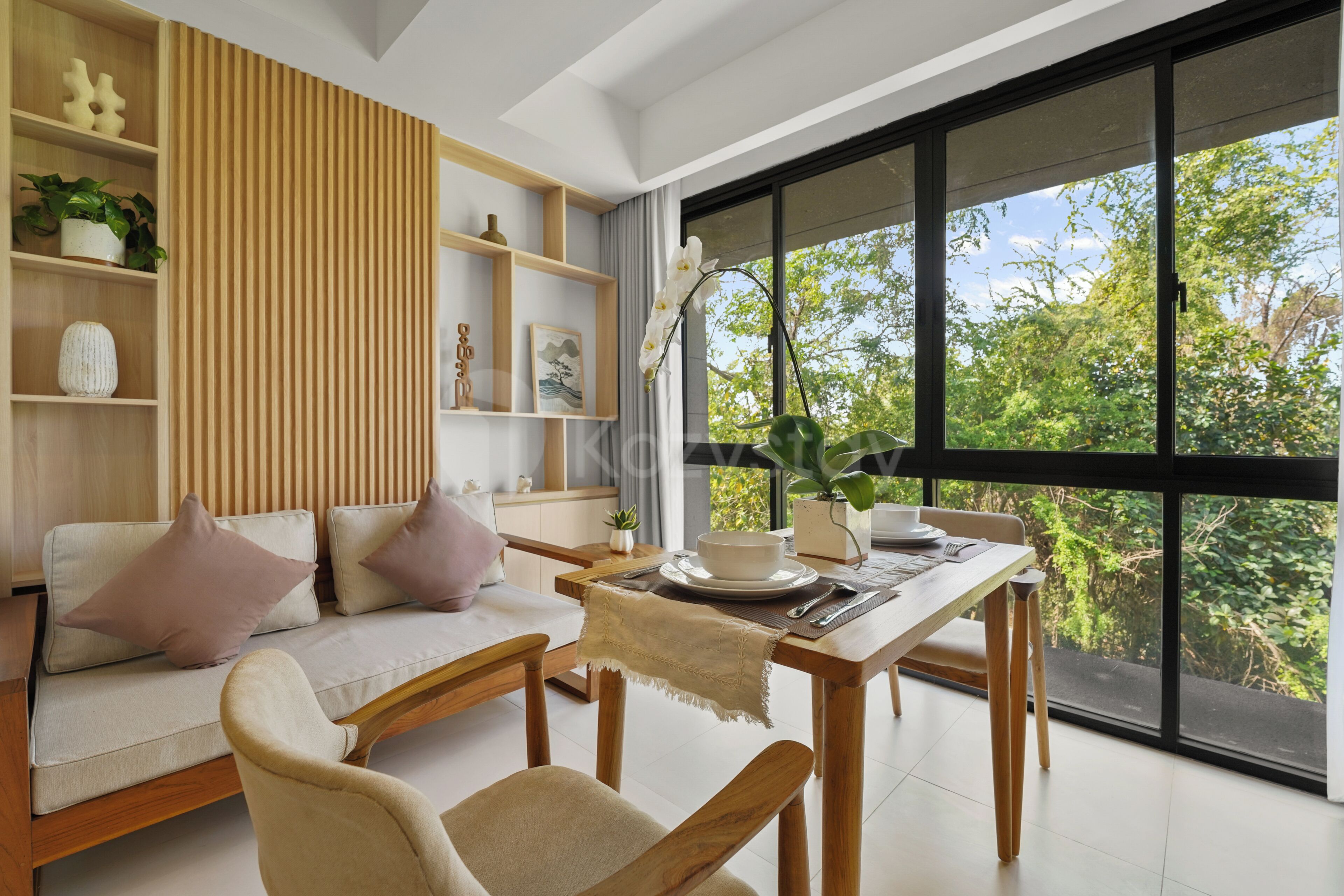 A modern living room with a sofa, dining table, and large windows.