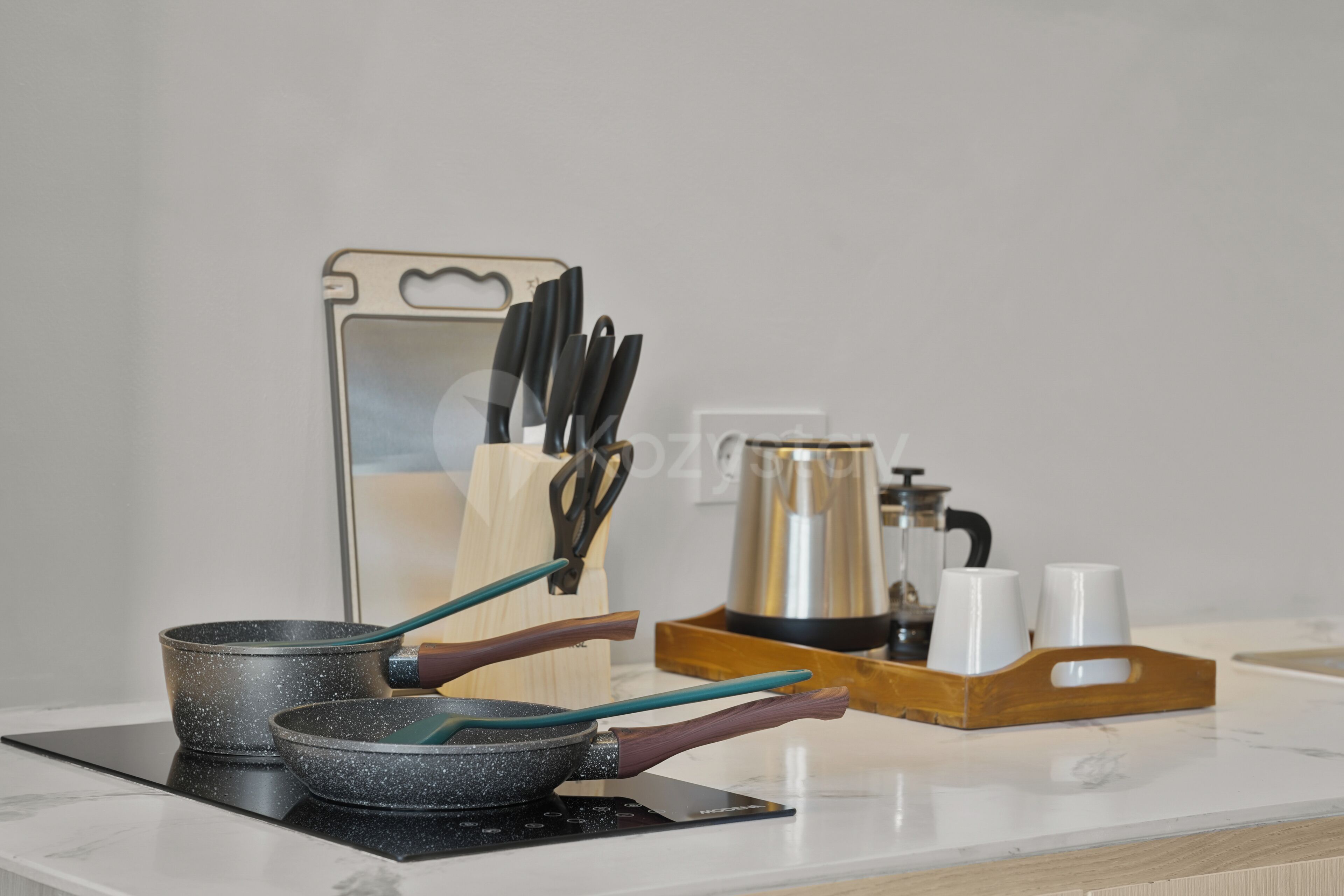 A kitchen counter with a frying pan, a kettle, and a coffee maker.
