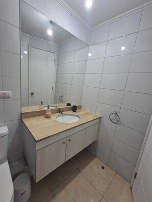 Baño con lavamanos, espejo e inodoro.
