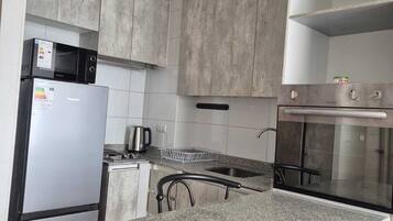 Una cocina equipada con microondas, refrigerador, estufa y horno.