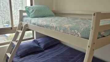 Una cama litera con escalera, una ventana con persianas y vistas a edificios.