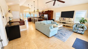 A spacious living area with a sofa, coffee table, and a dining area with chairs. - Ocean Front 6bed/6bath, gourmet kit, heated pool, private beach access (Ocean Isle Beach)