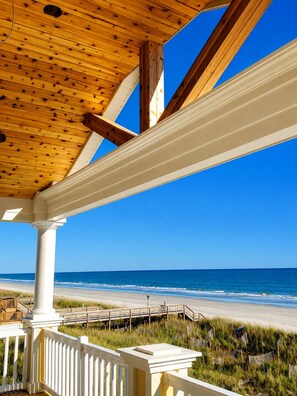 A wooden ceiling structure with white columns and a view of the beach. - Ocean Front 6bed/6bath, gourmet kit, heated pool, private beach access (Ocean Isle Beach)