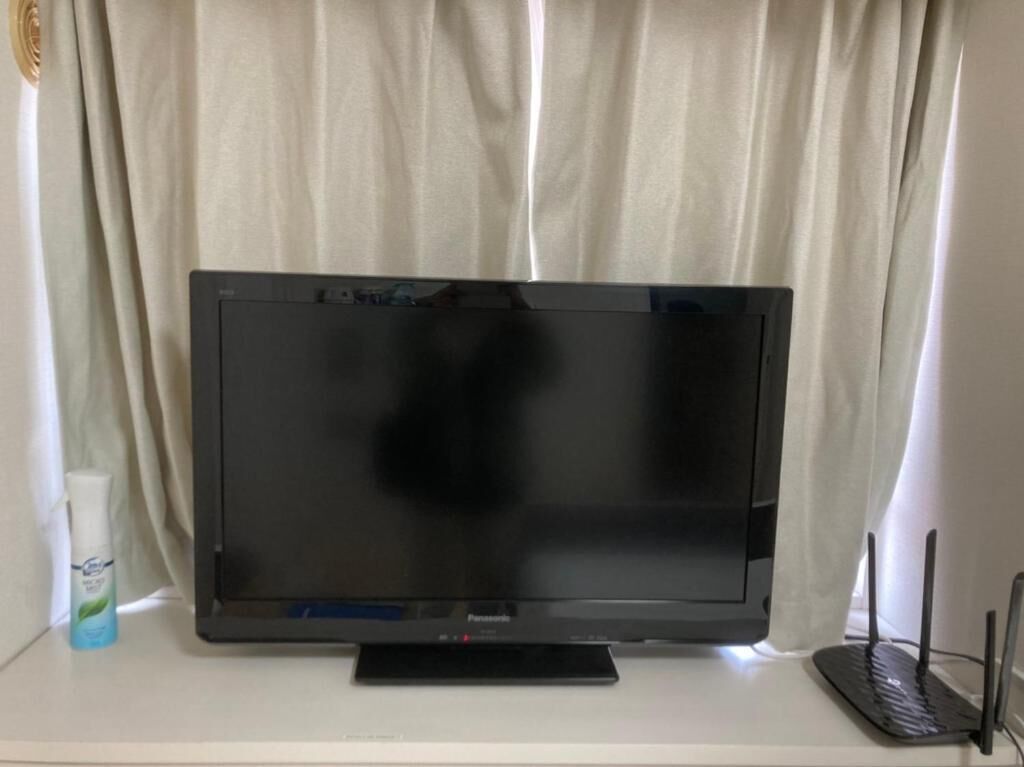 A flat-screen television on a stand with a remote control.