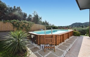 Een hottub met een houten buitenkant, omgeven door een pad van kiezels en een houten terras.