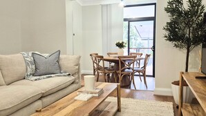 Ein Wohnzimmer mit einer Couch, einem Couchtisch und einem Esstisch mit Stühlen.