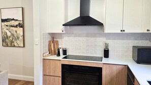 A modern kitchen with white cabinets, a black range hood, a microwave, and a dishwasher. - Newly Renovated 4-Bedroom Retreat in East Tamworth (East Tamworth)