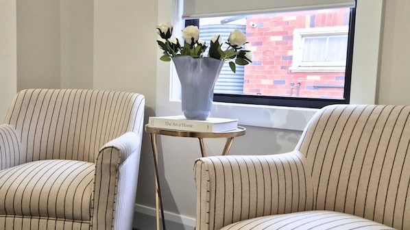 Two striped armchairs, a small table with a vase of white flowers, and a book titled 'The Art of Home' on the table. - Newly Renovated 4-Bedroom Retreat in East Tamworth (East Tamworth)