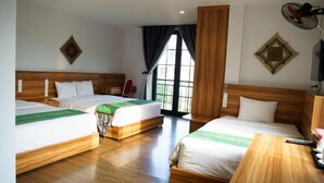 Quarto de hotel com três camas, cabeceiras de madeira e uma janela grande com cortinas.