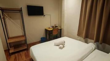 Habitación de hotel con cama, escritorio, silla, televisión y ventana con cortinas.