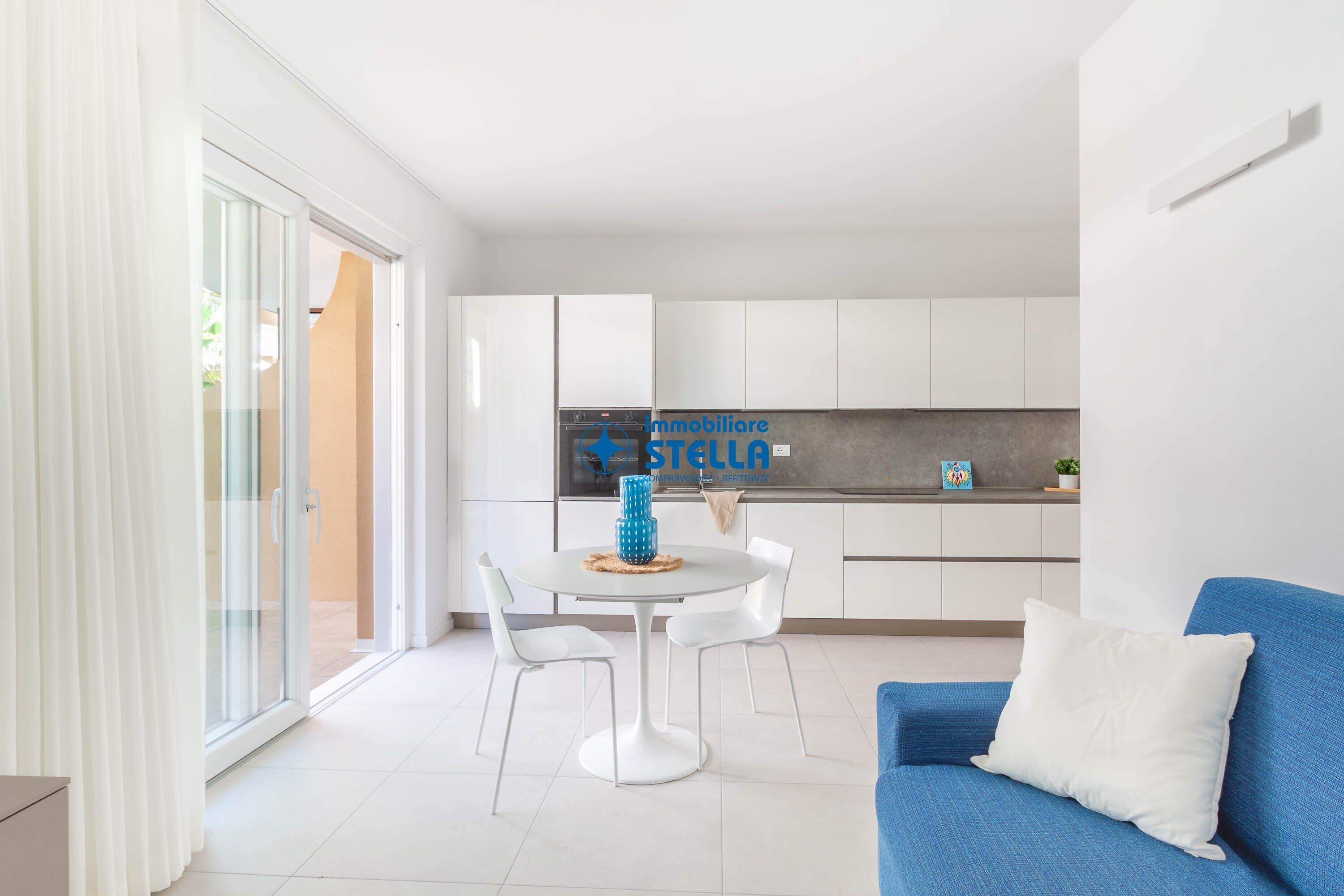 Un appartement moderne comprenant un coin repas, une kitchenette et un canapé bleu.
