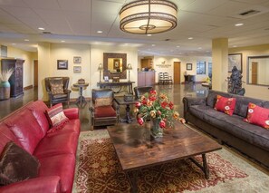 Eine geräumige Lobby mit Ledersofas, einem Holztisch und einem Kronleuchter.